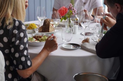 Grande tente éclairée la nuit, entourée de personnes et d'arbres, dans un cadre extérieur sombre.