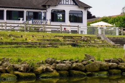 Grande tente éclairée la nuit, entourée de personnes et d'arbres, dans un cadre extérieur sombre.