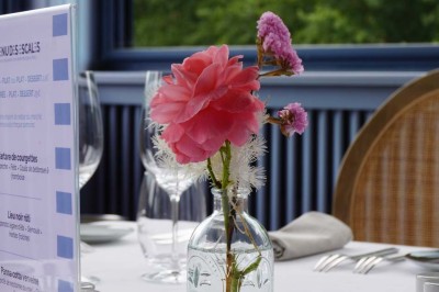 Grande tente éclairée la nuit, entourée de personnes et d'arbres, dans un cadre extérieur sombre.