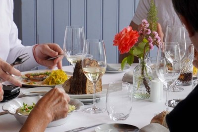 Grande tente éclairée la nuit, entourée de personnes et d'arbres, dans un cadre extérieur sombre.