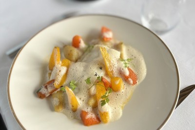 Grande tente éclairée la nuit, entourée de personnes et d'arbres, dans un cadre extérieur sombre.