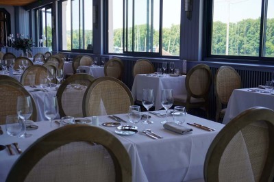 Maquette de voilier avec une grande voile blanche exposée devant un mur bleu orné de cadres et d'une applique murale.