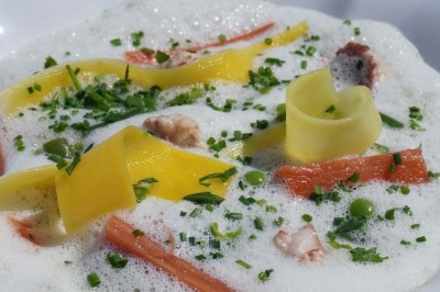 Maquette de voilier avec une grande voile blanche exposée devant un mur bleu orné de cadres et d'une applique murale.