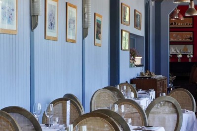 Maquette de voilier avec une grande voile blanche exposée devant un mur bleu orné de cadres et d'une applique murale.