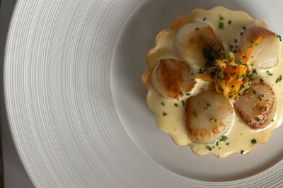 Maquette de voilier avec une grande voile blanche exposée devant un mur bleu orné de cadres et d'une applique murale.