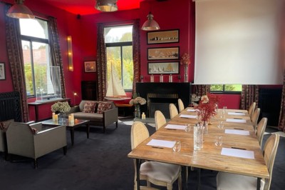 Salle de réunion avec une table en bois, des chaises en osier, des bouteilles d'eau et des documents, vue sur l'extérieur.