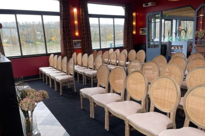 Salle de réunion avec une table en bois, des chaises en osier, des bouteilles d'eau et des documents, vue sur l'extérieur.
