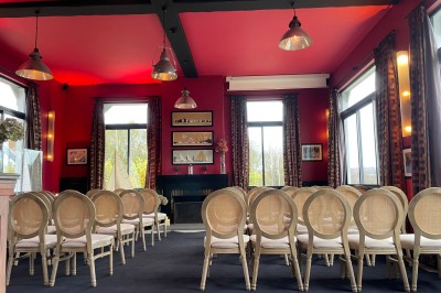 Salle de réunion avec une table en bois, des chaises en osier, des bouteilles d'eau et des documents, vue sur l'extérieur.