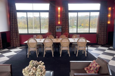 Salle de réunion avec une table en bois, des chaises en osier, des bouteilles d'eau et des documents, vue sur l'extérieur.