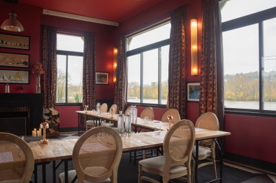 Salle de réunion avec une table en bois, des chaises en osier, des bouteilles d'eau et des documents, vue sur l'extérieur.