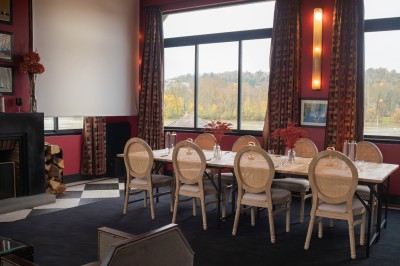 Salle de réunion avec une table en bois, des chaises en osier, des bouteilles d'eau et des documents, vue sur l'extérieur.