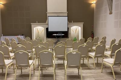 Abri extérieur avec toit en tuiles et structure métallique, situé sur une terrasse en béton près d'un bâtiment en pierre.