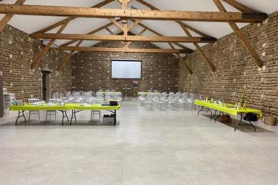 Abri extérieur avec toit en tuiles et structure métallique, situé sur une terrasse en béton près d'un bâtiment en pierre.