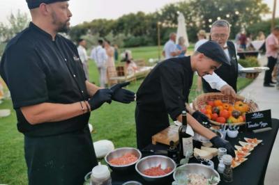 Abri extérieur avec toit en tuiles et structure métallique, situé sur une terrasse en béton près d'un bâtiment en pierre.