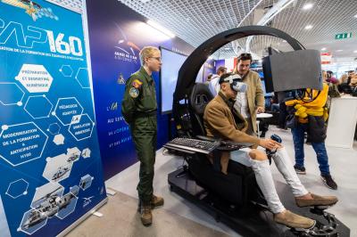 Vue aérienne d'une péninsule boisée entourée de mer, avec des montagnes enneigées à l'horizon.