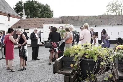 Terrasse en bois avec salon de jardin, sauna en forme de tonneau, jacuzzi et clôture en bois, entourée de verdure.