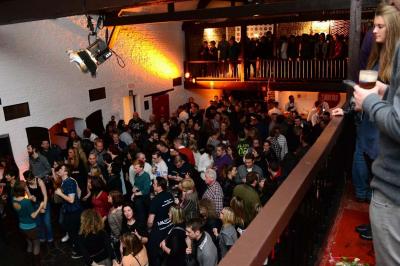 Salle de réception décorée avec des tables rondes, nappes blanches, chaises houssées et éclairage tamisé.