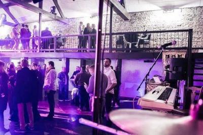 Salle de réception décorée avec des tables rondes, nappes blanches, chaises houssées et éclairage tamisé.