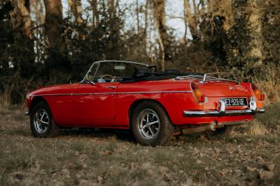 Miniature Voitures Passion #2 Roue avant d'une voiture vintage beige avec un enjoliveur chromé, stationnée sur un sol gravillonné.