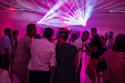 Groupe de personnes levant les bras lors d'un concert ou d'un événement avec des lumières vives en arrière-plan.