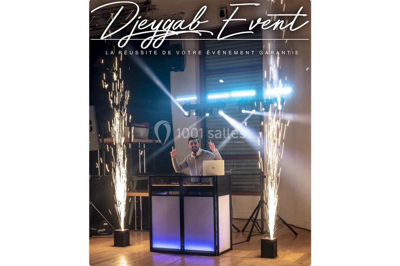 Un DJ mixant derrière une table éclairée, entouré d'effets lumineux et de jets d'étincelles en intérieur.