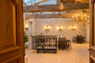 Salle à manger chaleureuse avec poutres apparentes, tables dressées, chaises rouges et cheminée en pierre.