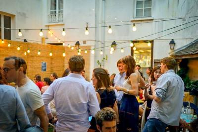 Salle à manger chaleureuse avec poutres apparentes, tables dressées, chaises rouges et cheminée en pierre.