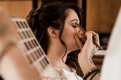Main avec un tatouage de triangles entrelacés, posée sur des cheveux bruns, bracelet en perles noires visible.