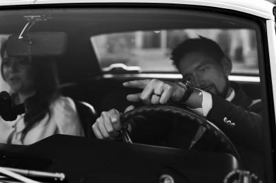 Main avec un tatouage de triangles entrelacés, posée sur des cheveux bruns, bracelet en perles noires visible.