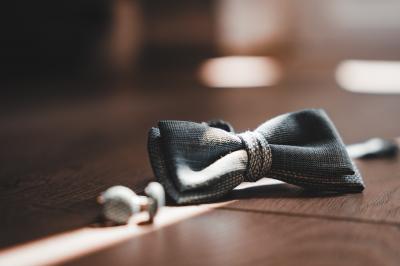 Main avec un tatouage de triangles entrelacés, posée sur des cheveux bruns, bracelet en perles noires visible.