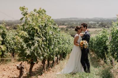 Un couple assis lors d'une cérémonie, l'homme ému essuie une larme tandis que la femme le regarde avec tendresse.