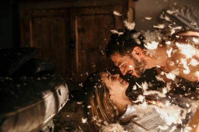 Un couple assis lors d'une cérémonie, l'homme ému essuie une larme tandis que la femme le regarde avec tendresse.