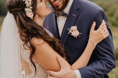 Un couple assis lors d'une cérémonie, l'homme ému essuie une larme tandis que la femme le regarde avec tendresse.