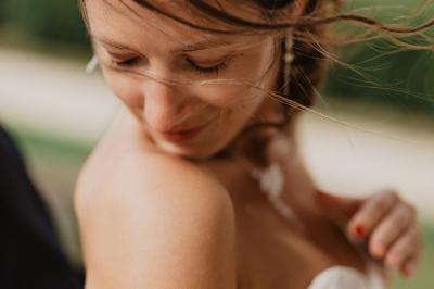 Un couple assis lors d'une cérémonie, l'homme ému essuie une larme tandis que la femme le regarde avec tendresse.