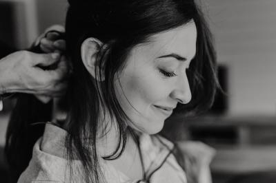 Un couple assis lors d'une cérémonie, l'homme ému essuie une larme tandis que la femme le regarde avec tendresse.