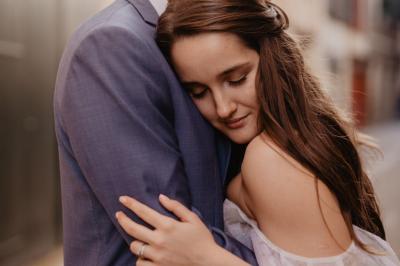 Un couple assis lors d'une cérémonie, l'homme ému essuie une larme tandis que la femme le regarde avec tendresse.