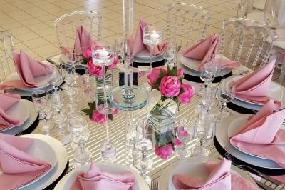 Salle de réception décorée avec des tables rondes, des chaises blanches, des chandeliers et des drapés blancs au plafond.