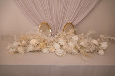Salle de réception décorée avec des tables rondes, des chaises blanches, des chandeliers et des drapés blancs au plafond.