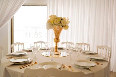 Salle de réception décorée avec des tables rondes, des chaises blanches, des chandeliers et des drapés blancs au plafond.
