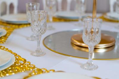 Salle de réception décorée avec des tables rondes, des chaises blanches, des chandeliers et des drapés blancs au plafond.