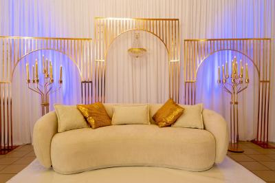 Salle de réception décorée avec des tables rondes, des chaises blanches, des chandeliers et des drapés blancs au plafond.