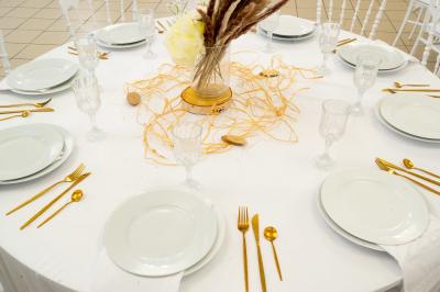 Salle de réception décorée avec des tables rondes, des chaises blanches, des chandeliers et des drapés blancs au plafond.