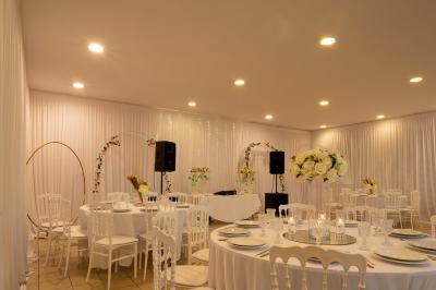Salle de réception décorée avec des tables rondes, des chaises blanches, des chandeliers et des drapés blancs au plafond.
