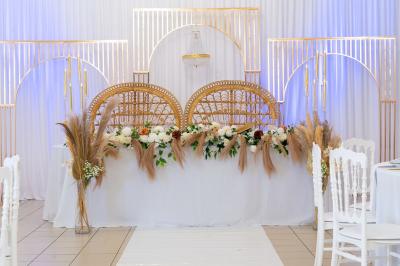 Salle de réception décorée avec des tables rondes, des chaises blanches, des chandeliers et des drapés blancs au plafond.