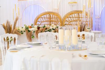Salle de réception décorée avec des tables rondes, des chaises blanches, des chandeliers et des drapés blancs au plafond.