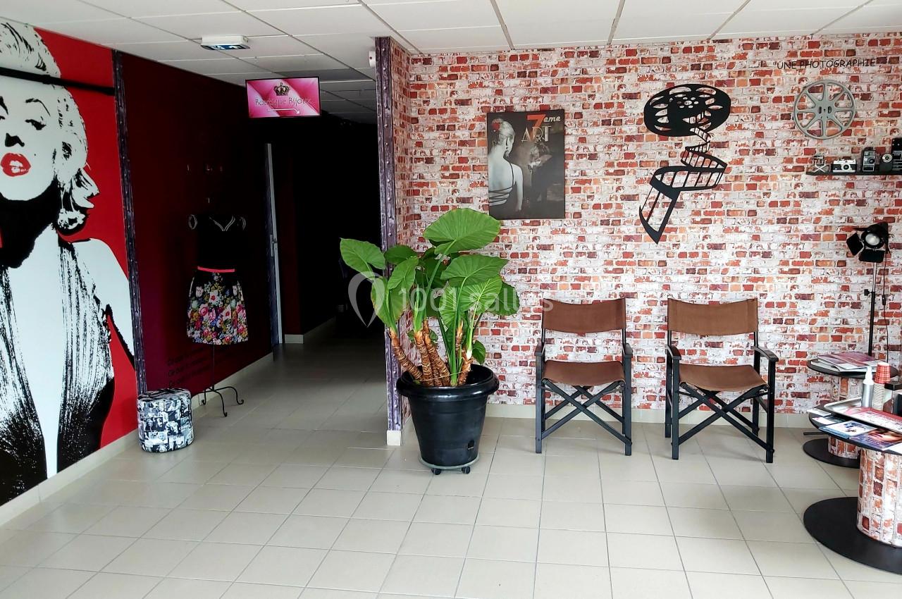 Mur décoré de motifs cinéma, plante en pot, deux chaises en bois et éléments de décoration rétro.