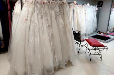 Robes élégantes sur mannequins et vêtements suspendus dans une pièce lumineuse avec rangements et cintres.