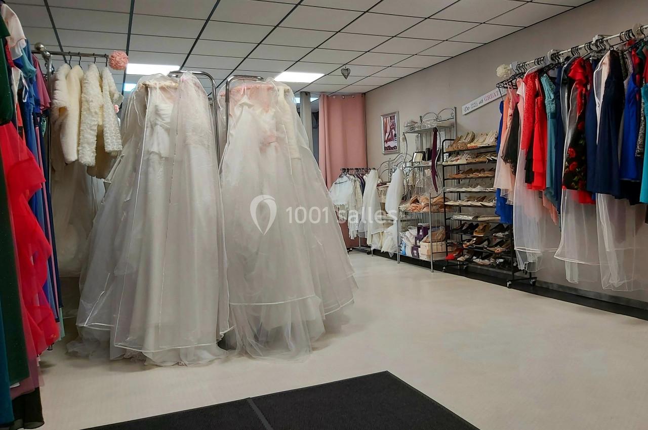 Robes de mariée blanches sur des portants, entourées de vêtements colorés et d'accessoires dans une boutique.
