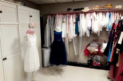 Robes élégantes sur mannequins et vêtements suspendus dans une pièce lumineuse avec rangements et cintres.