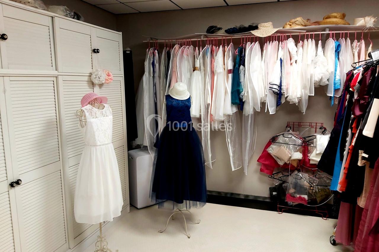 Robes élégantes sur mannequins et vêtements suspendus dans une pièce lumineuse avec rangements et cintres.